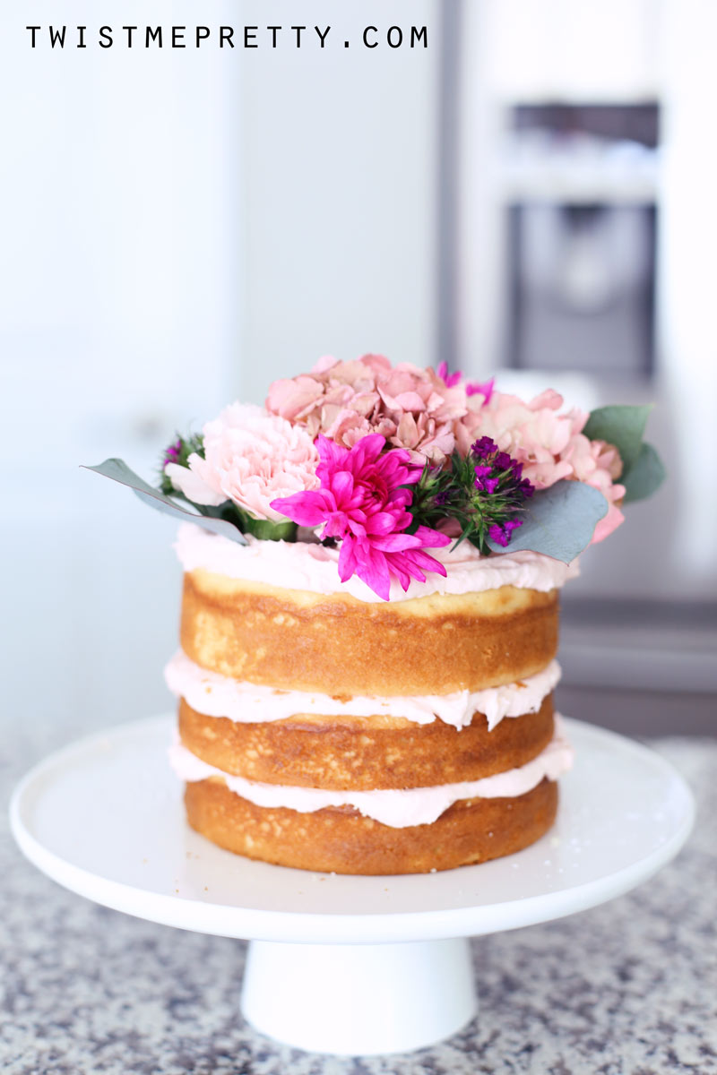 Side-view of a naked cake, decorated with flower. Twist Me Pretty.