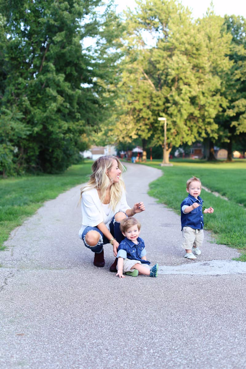 A mother bends down and smiles at her twin boys. Enjoy motherhood. Twist Me Pretty.