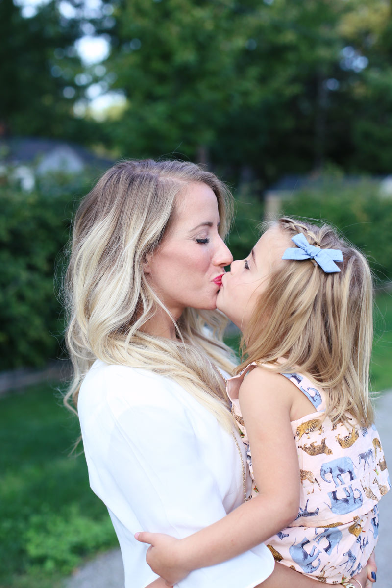 Motherly love. A mother kisses her daughter on the lips. Enjoy motherhood with Twist Me Pretty.