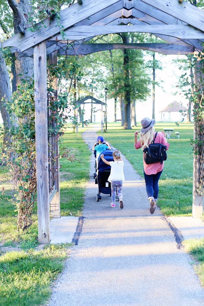 Abby and her kids walk through a beautiful park, with each of the older children pushing a baby jogger stroller.