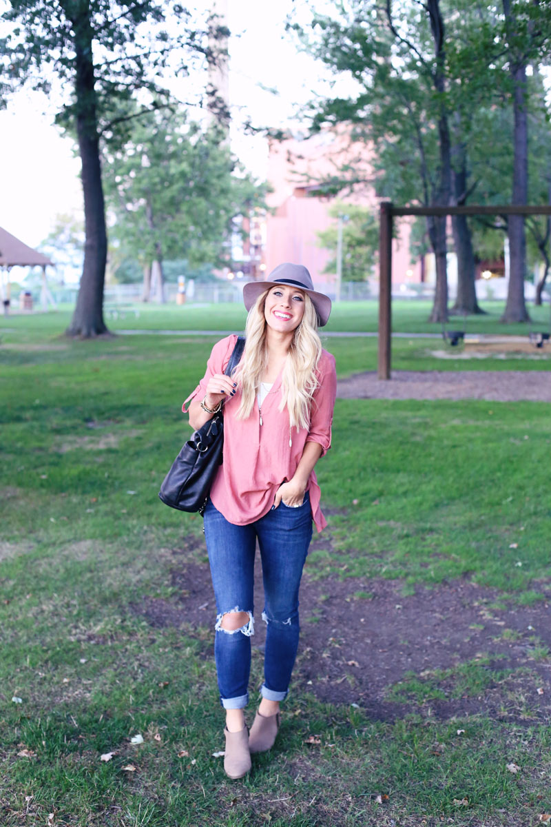 Abby looks comfy but classy in torn jeans, tan booties, a hat, a flowy peach shirt and an oversized handbag.
