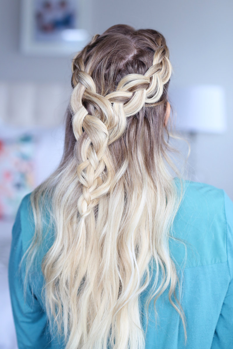 A blonde woman faces away from the camera, her hair cascading down her back. Two braids come around each side of her head and meet at the back. Dutch braid hairstyles tutorial.