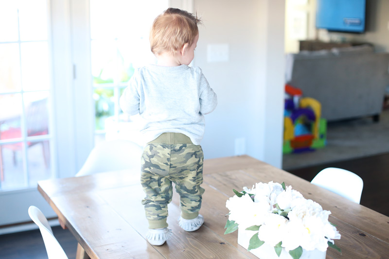 Toddler, standing on a dining room table.