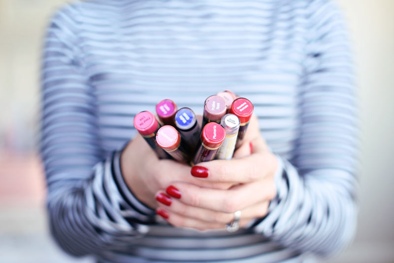 A woman holds out indelible lipstains in various colors. Twist Me Pretty.