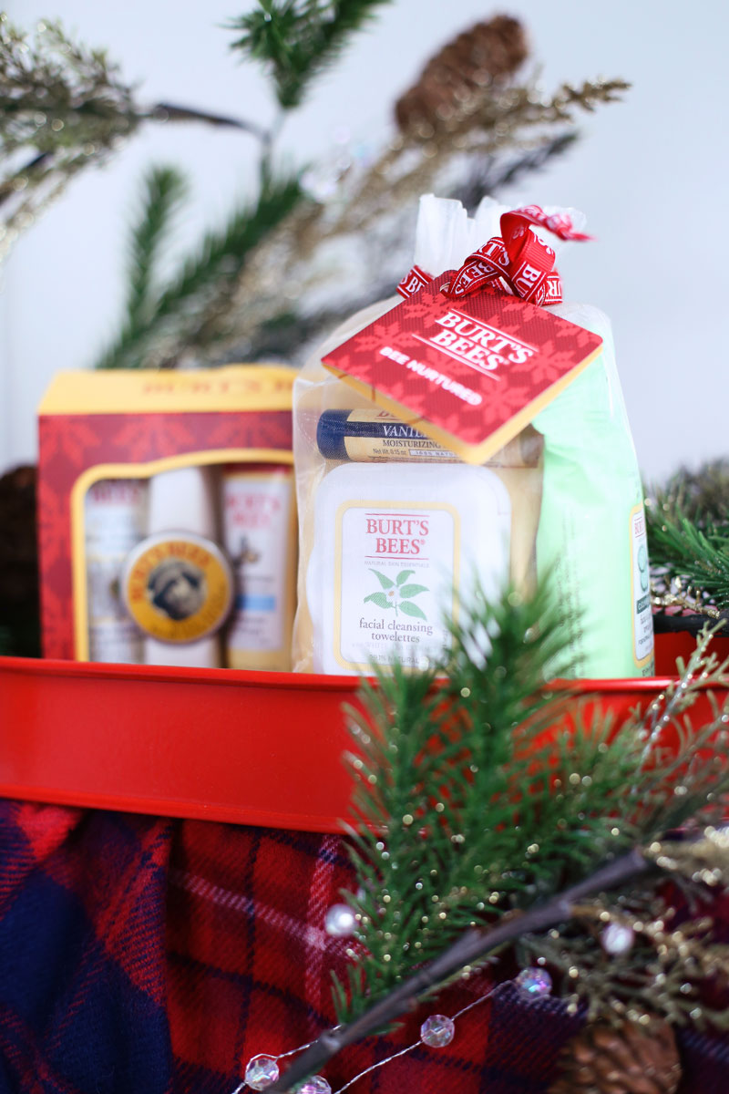 A festive photo of Burt's Bees' holiday gift sets on a tartan cloth with sprigs of festive pine trees. Find out at Twist Me Pretty.