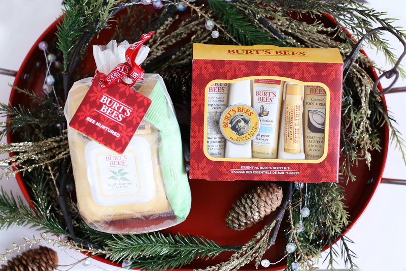 Burt's Bees' festive holiday gift sets, including the Bee Natural pack, sit in a red barrel surrounded by pine cones and leaves. Find out more at Twist Me Pretty.